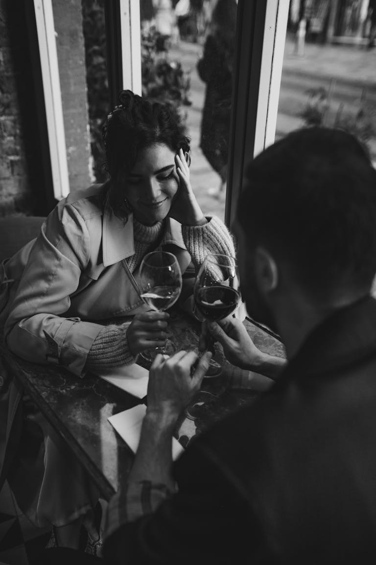 Black and white image of a couple enjoying a wine date indoors, capturing intimate and romantic vibes.
